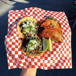 three tacos on a plate with red and white restaurant paper
