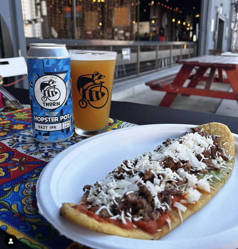 photo of a mulita and a thorn beer can and pint of beer out in front of the Thorn Brewing tasting room in barrio logan.